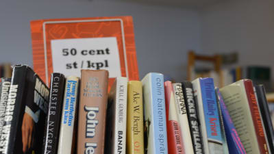 En bild på böcker på en bokhylla och en skylt där det står 50 cent per bok.