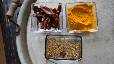 Gurkmeja, torkad chili och kadhai masala i olika skålar på en bricka