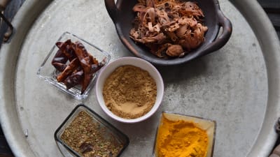 Olika kryddor till indiskgryta på en bricka i ett kök