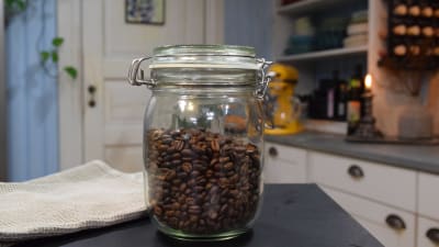 Rostade kaffebönor i en glasburk på ett bord