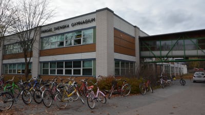 Pargas svenska gymnasiums byggnad i ljusa och bruna tegel, med cyklar parkerade utanför.