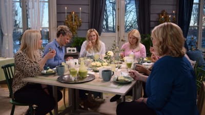 En grupp kvinnor som sitter och äter runt ett bord. De firar en baby shower.