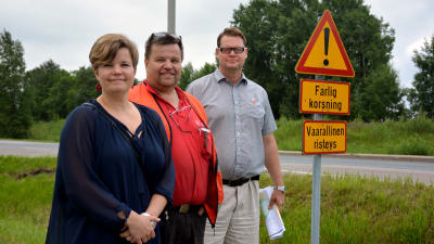 Mia Skog, Ulf Österman och Jan Gröndahl står vid en skylt där det står "farlig korsning".