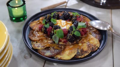  Musta astia, jossa kasa lettuja. Letuilla on vadelmia, karhunvatukoita, creme fraichea ja karamellikastiketta.