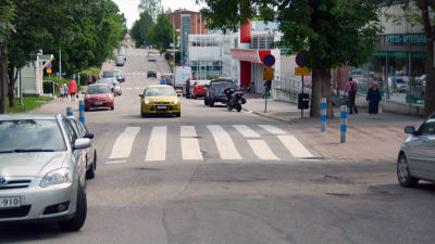 En bil kör framför ett övergångsställe på en gata.