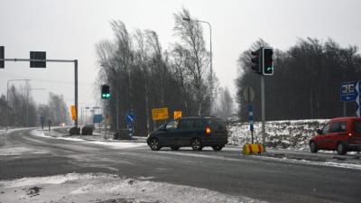 En bil kör till vänster i en korsning med trafikljus.