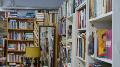En bild på mängder avfärgglada böcker i bokhyllor.
