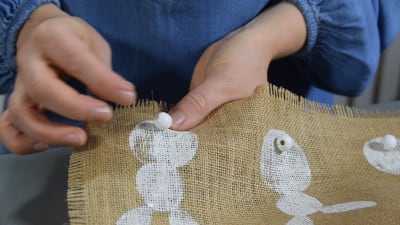 hand syr fast pärla på ett kanintryck på en duk