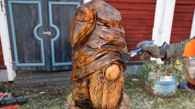 En träskulptur som föreställer en tomte oljas in med pensel.