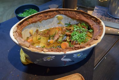 En stor keramikgryta med en kött- och potatisrätt i.