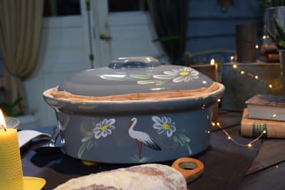 Ett matbord där det står en stor terrin som är grå och har en målad stork och blommor på.