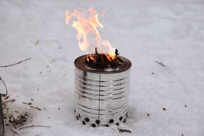 En konservburk som gjorts till en liten eldstad. I konservburken brinner torrt ris.