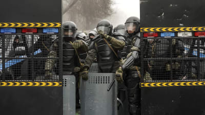 Kravallpolis i Almity i Kazakstan som skyddar sig bakom sköldar och galler.