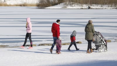 En familj ute på promenad i vinterväder.