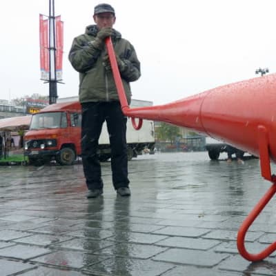 Mies puhaltaa jättitorveen nykytaidetapahtuma Anti-festivaalilla Kuopion torilla.