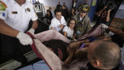 Brandmän räddar en flicka från eldsvåda på ett barnhem i Guatemala den 8 mars 2017. Branden krävde ett tjugotal dödsoffer.