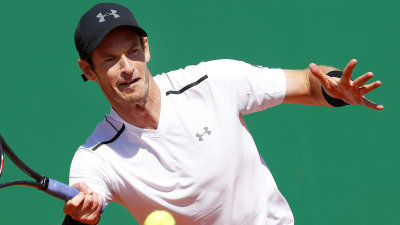 Vitklädde tennisspelaren Andy Murray slår en tennisboll.
