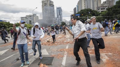 Demonstranter flyr undan säkerhetsstyrkor i centrum av Caracas 30.7.2017.