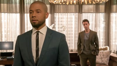 En man står i kostym vänd mot kameran och ser allvarlig ut. I bakgrunden en man som tittar på honom fundersamt. De står i ett kontor i tv-serien Empire.