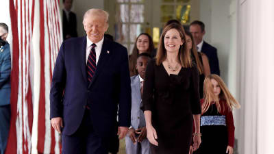 USA:s president Donald Trump går bredvid Amy Coney Barrett. Båda ler. Bakom dem står Coney Barretts barn.