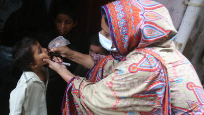 En hälsovårdsarbetare ger poliovaccindroppar till ett barn.