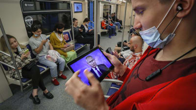 Mies katsoo metrossa Putinia kännykästään.