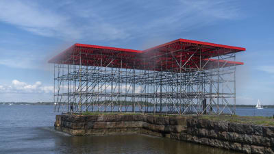 En stor konstruktion av byggnadsställningar och röd plattform vid kajen på Skanslandet.
