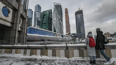 En kvinna och en man står och tittar upp mot skyskraporna i Moskvas finanskvarter.