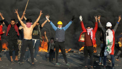 Unga irakiska demonstranter visar segertecknet mitt under sammandrabbningar med kravallpolis i Bagdad på måndagen. 