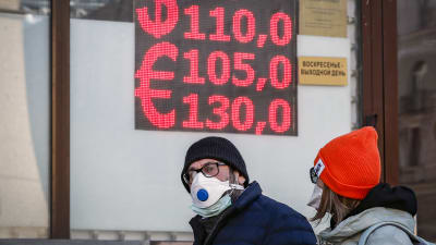 Människor går framför en valutaväxlingskontor i Moskva.