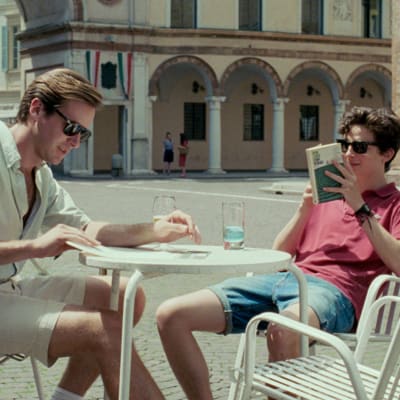 Oliver (Armie Hammer) och Elio (Timothée Chalamet) sitter vid en utomhusservering och pratar. 