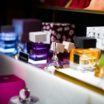 Parfyymipulloja ja muuta tarpeistoa valaistulla pöydällä.
