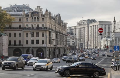 Musta Mercedes-Benz-henkilöauto on kääntymässä vilkkaalle valtaväylälle Moskovan keskustassa. Taustalla näkyy valtiollisen duuman rakennus.