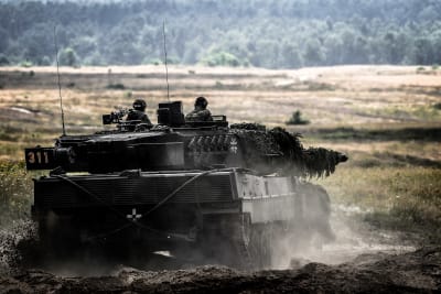 Två personer som sitter i en Leopard 2-pansarvagn.