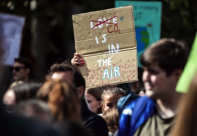 En klimatdemonstrant med ett plakat med texten "CO2 is in the air."
