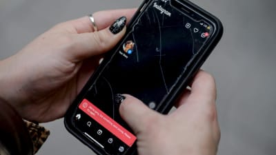 Två händer som håller i en mobiltelefon med flera sprickor på skärmen. Nertill på skärmen finns en röd balk med ett felmeddelande. 
