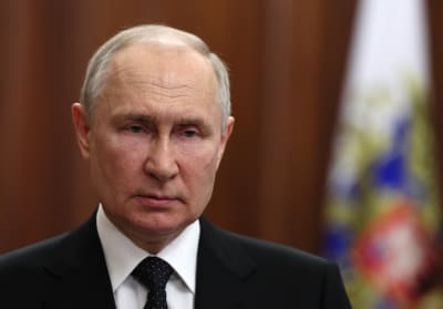 Vladimir Putin i förgrunden, i bakgrunden Rysslands flagga.