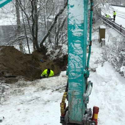 Ihmiset korjaavat vesijohtoa auki kaivetussa montussa.