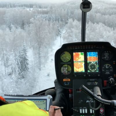 Helikopteri lentää sähkölinjan yllä.