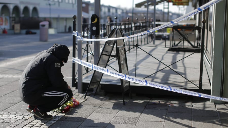 En man lägger ner blommor utanför den restaurang i Göteborg där en gängrelaterad dödsskjutning ägde rum 18.3.2015