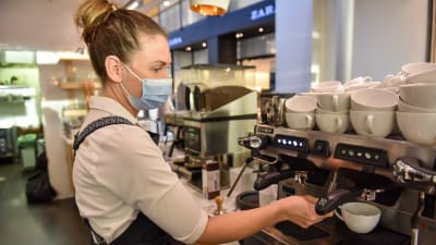 Försäljare på ett kafe jobbar med en kaffemaskin. 