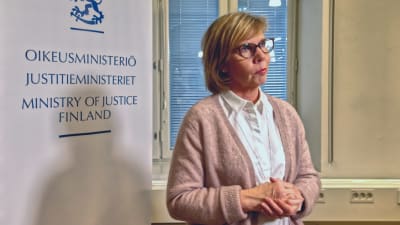 Justitieminister Anna-Maja Henriksson framför en plansch där det står Justitieministeriet. 