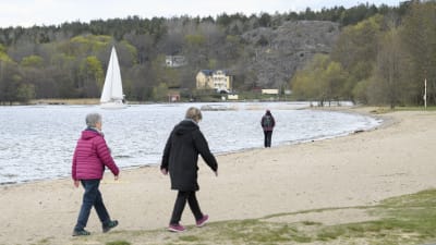 Människor promenerade längs en strand i Sätra, i sydöstra Stockholm den 25 april. 
