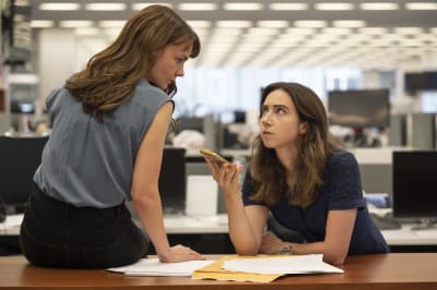 Megan Twohey (Carey Mulligan) och Jodi Kantor (Zoe Kazan) sitter vid ett bord och lyssnar på ett telefonsamtal samtidigt som de ser på varandra och ser allvarliga ut.