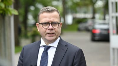 Petteri Orpo står utomhus och talar. 