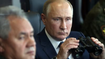 Rysslands president Vladimir Putin spanar med kikare i handen.
