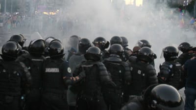 Rumänska demonstranter backar för kravallpoliser som kastat tårgas.