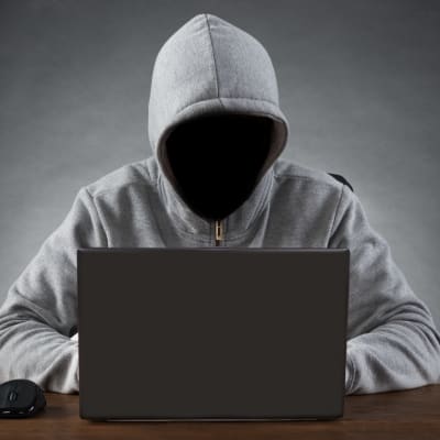 Anonym person framför en laptop
