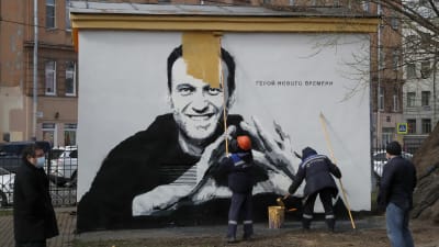 Arbetare målar över en väggmålning av Aleksej Navalnyj.