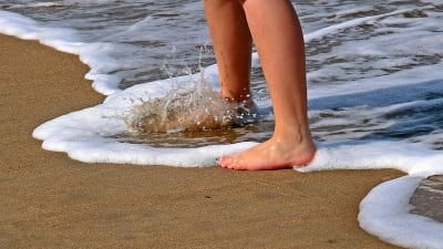 Bara fötter i sanden vid en strand